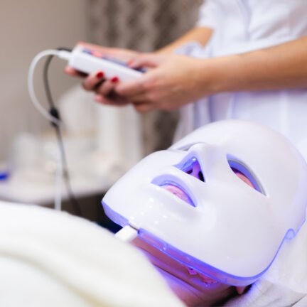 The client lies in the salon on the cosmetology table with a white mask on her face